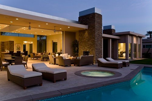 House exterior with sunloungers, recliners on patio by swimming pool